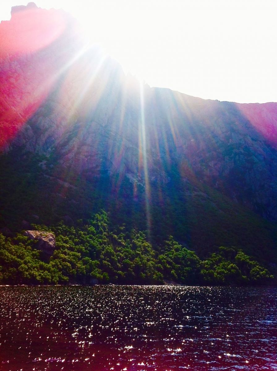 Sunlight creating blue and pink rays shining over the ocean 